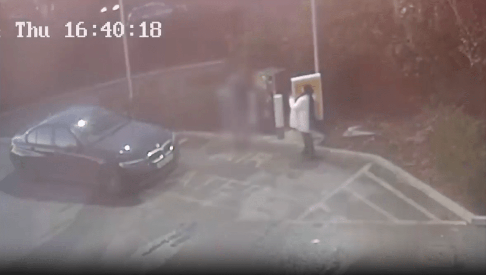 Security camera footage showing a person spray-painting a black car.