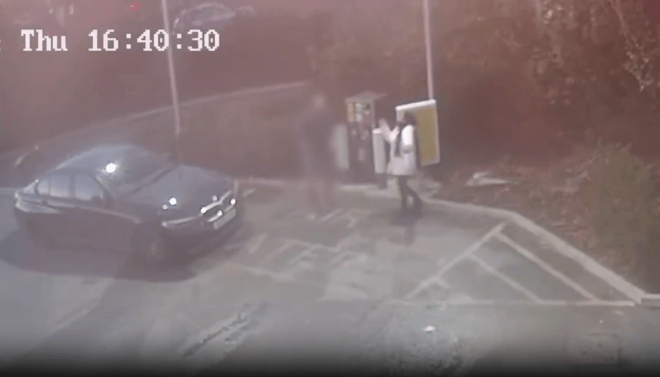 CCTV footage of a car parked at a gas station with two people nearby.