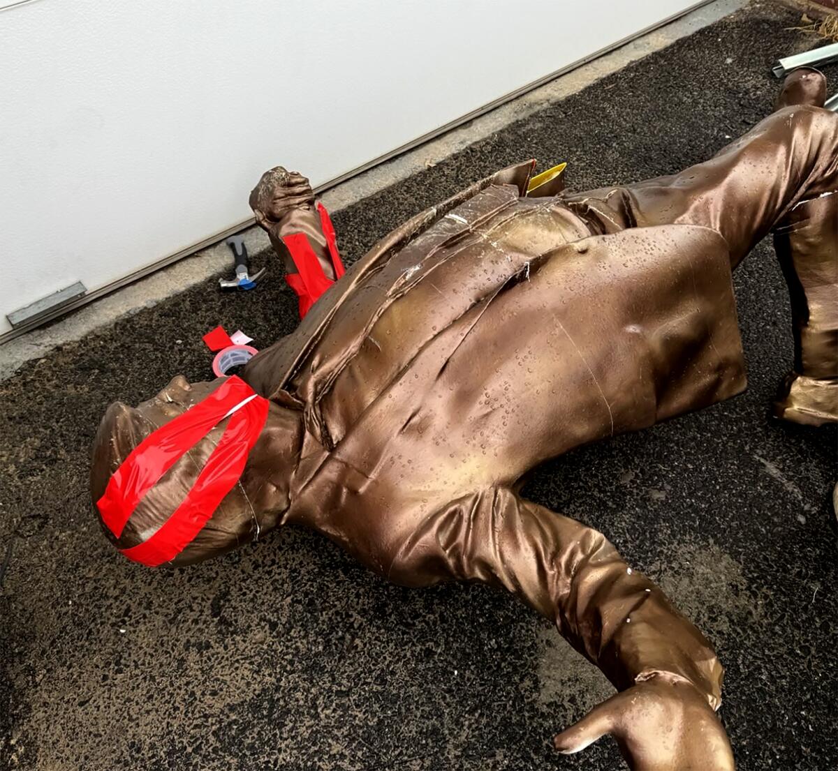 A bronze statue of President Trump with its broken head taped back together. 