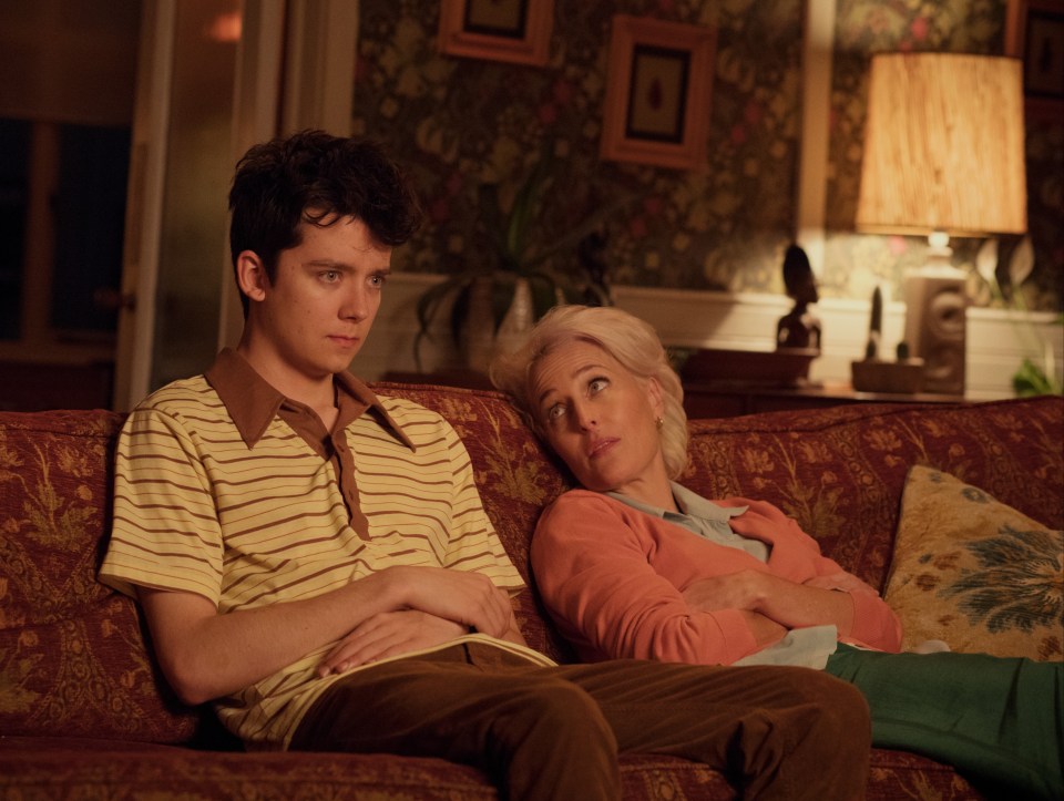 Asa Butterfield and Gillian Anderson on a red couch in "Sex Education".
