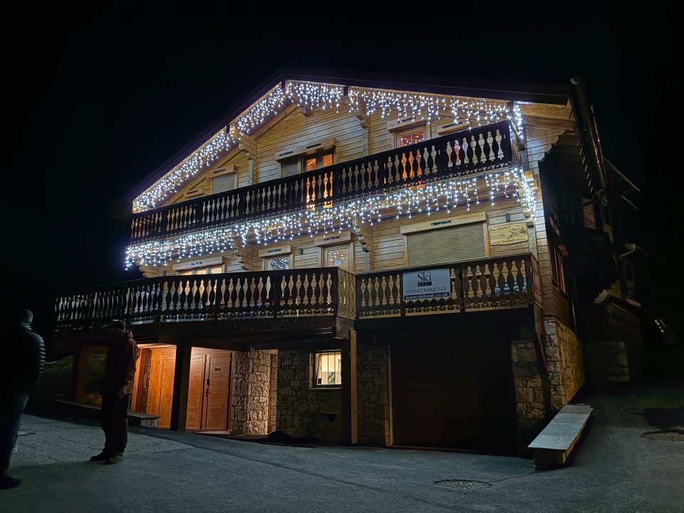 A wooden ski chalet with balconies and icicle lights.