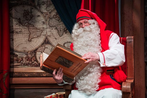 Santa Claus poses with a book at his office