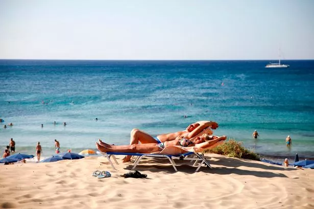 Tourists sunbathe at the beach in the resort town of Ayia Napa 