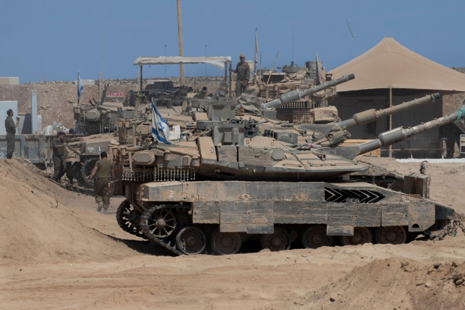Israeli IDF soldiers work on their tanks in a forward staging area near the Gaza Strip border.