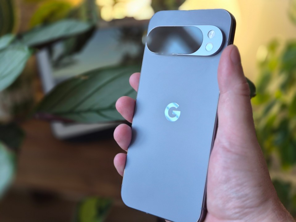 Hand holding a gray Google Pixel phone, showing the back with the camera bar and Google logo.
