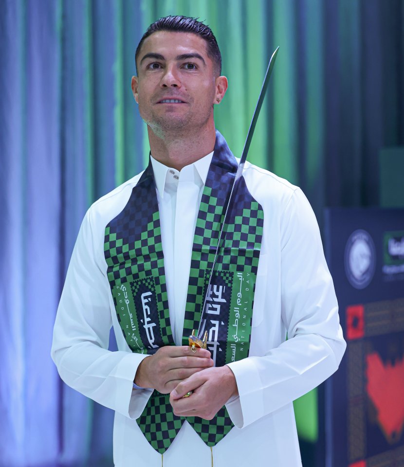 Cristiano Ronaldo in traditional Saudi attire, holding a ceremonial sword.