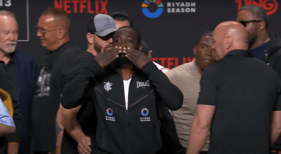 Screenshot of a boxer covering his face with his hands at a press conference.