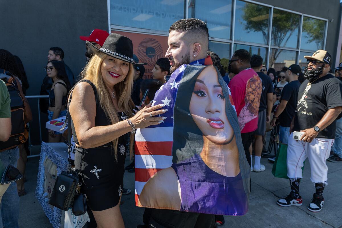 A man and woman stand smiling outside a record store.