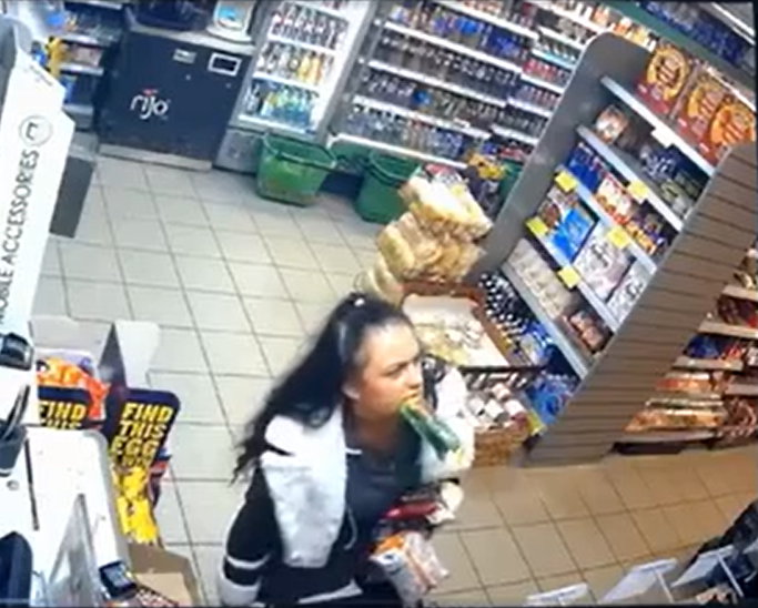 Surveillance image of a woman in a convenience store biting into a bottle.
