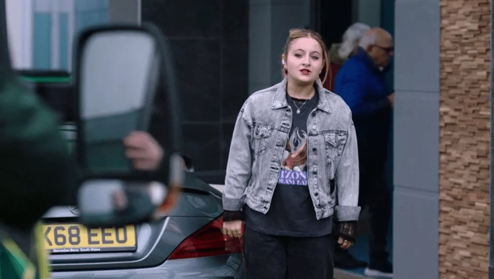 Young woman in denim jacket standing outside.