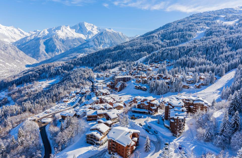 Aerial view of La Tania ski resort village in Tarentaise Valley with snowy chalets and Grand Bec Peak in the background.