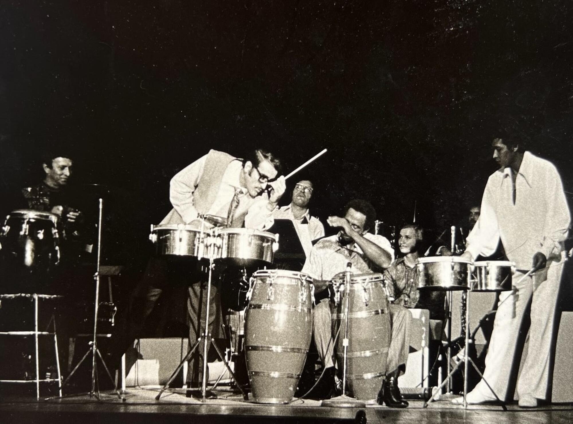 Walfredo de los Reyes Sr. plays congas on stage in a black and white photo