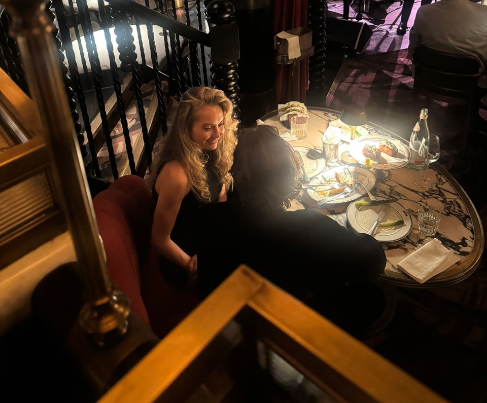 Pete Wicks and a blonde woman dining at The Maine Mayfair restaurant, with a band performing in the background.