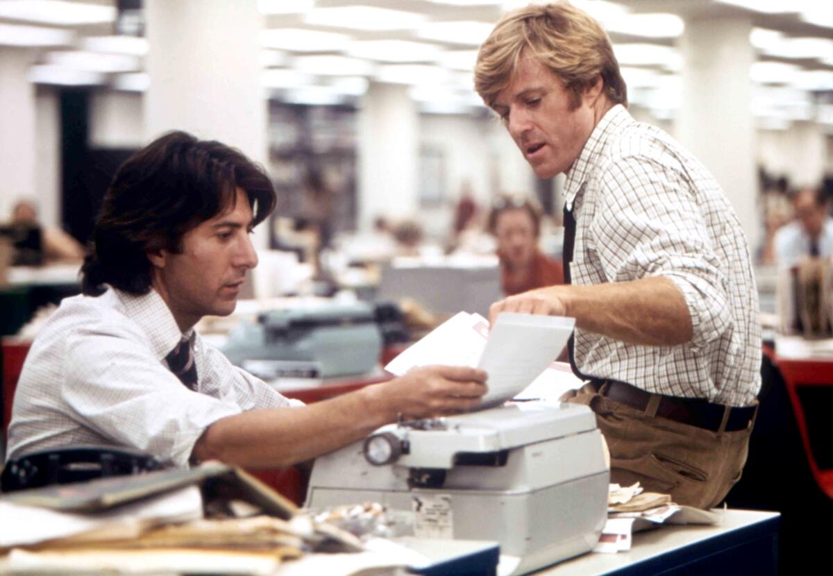 Two journalists collaborate on a story in a newsroom.