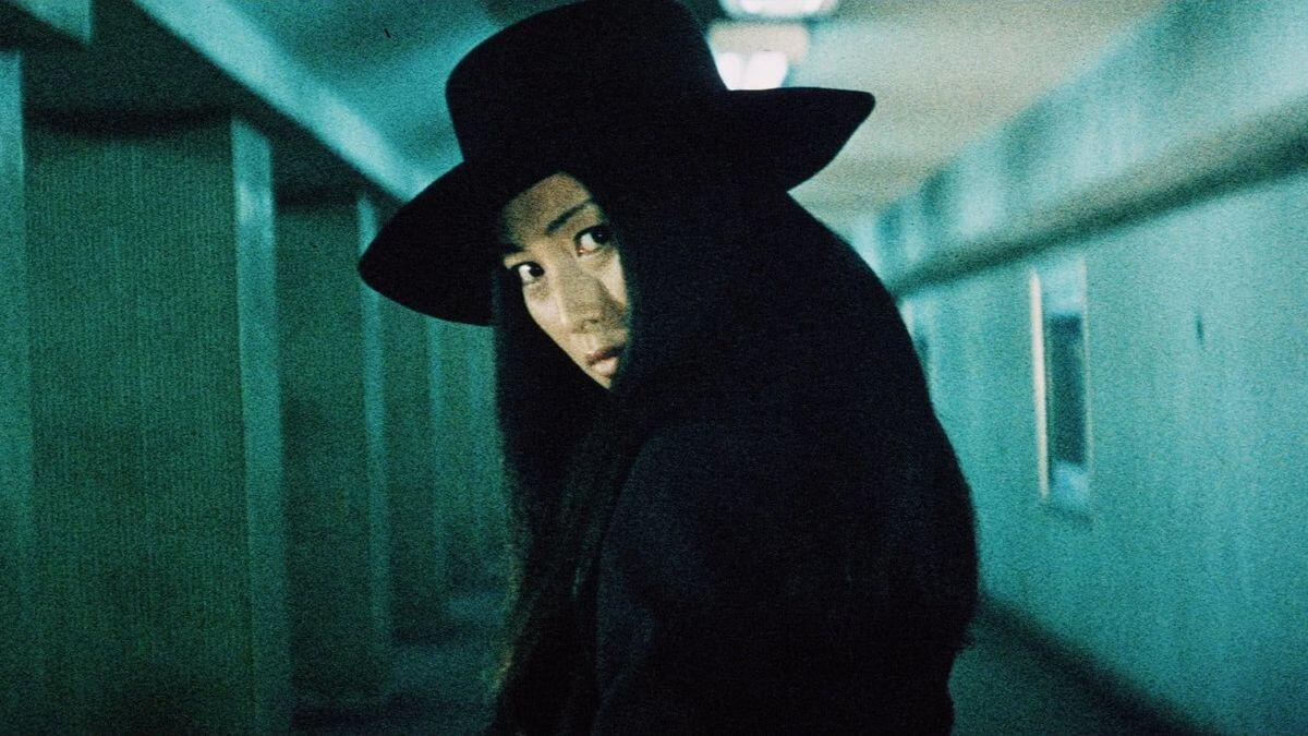 A woman in a black hat looks mysterious.
