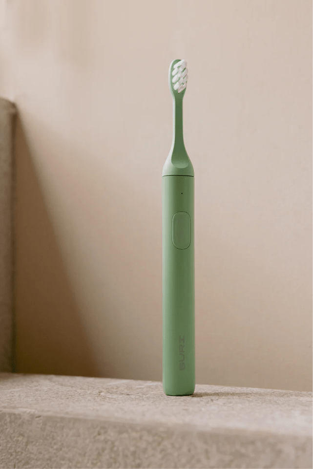 Sage green SURi electric toothbrush.