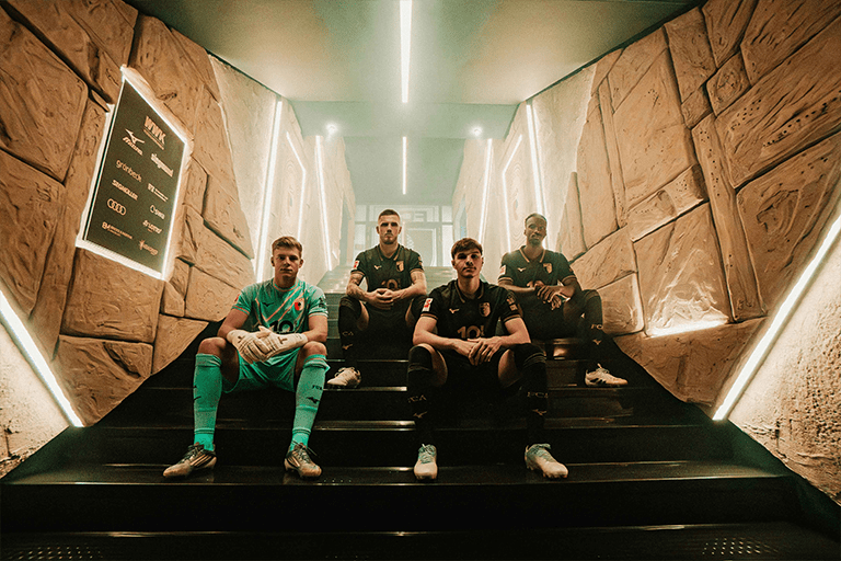 Four soccer players sitting on stairs.
