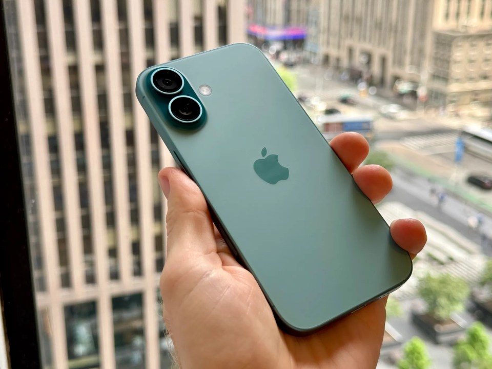 A hand holding a teal iPhone 16.