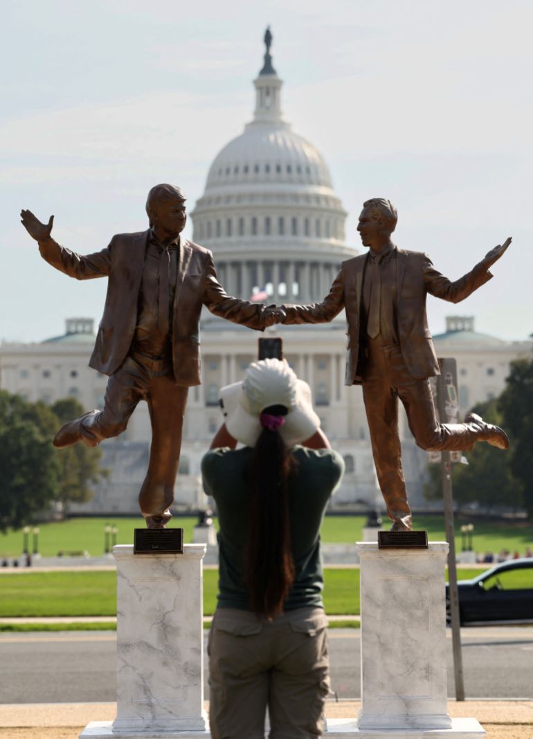 A woman takes a photo of a pop-up statue depicting U.S. President Donald Trump and disgraced financier and sex offender Jeffrey Epstein dancing together near the U.S. Capitol in Washington, D.C., U.S., September 23, 2025. REUTERS/Kevin Lamarque