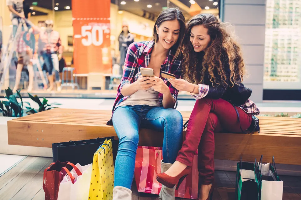 Two smiling women shopping online with a credit card.