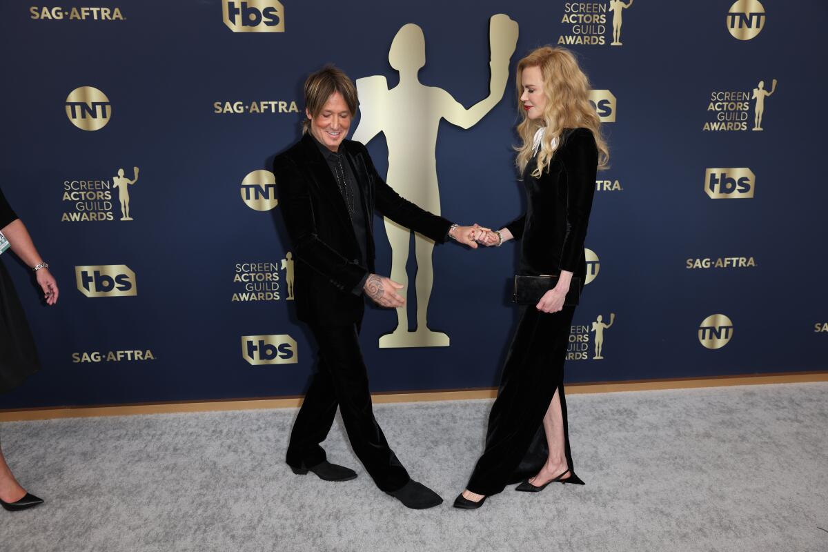 Keith Urban and Nicole Kidman hold hands while both showing off their shoes upon arrival at a formal event