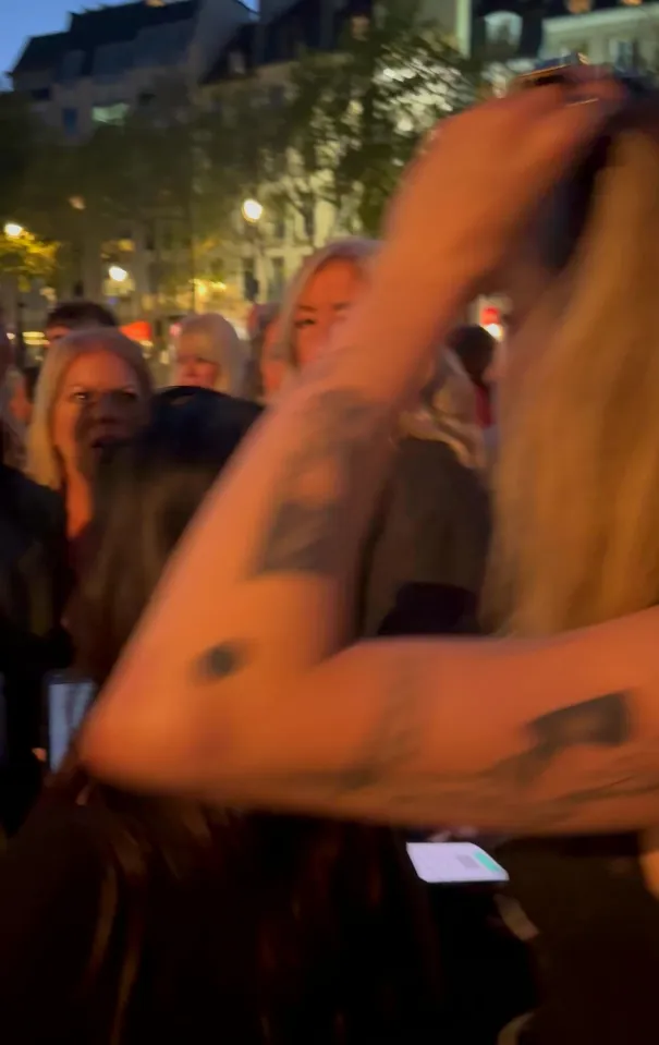 Cara Delevingne with tattooed arms holding up her long blonde hair at the Stella McCartney fashion show.