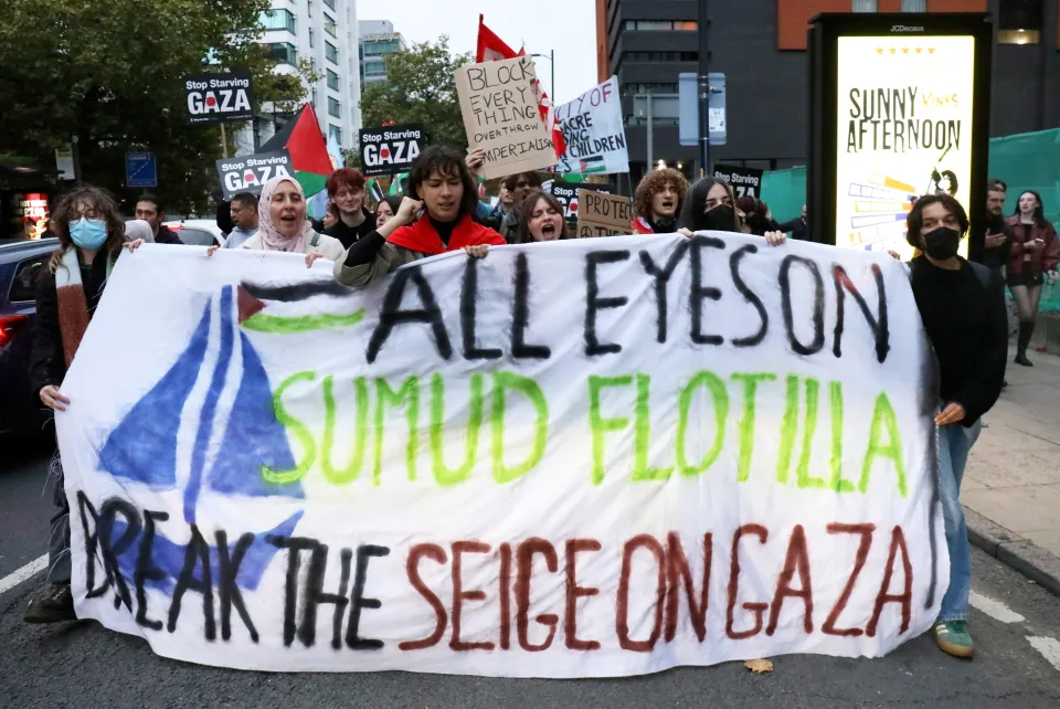 Pro-Palestinian protestors marching in Manchester, holding a large banner that reads "ALL EYES ON SUMUD FLOTILLA BREAK THE SIEGE ON GAZA."