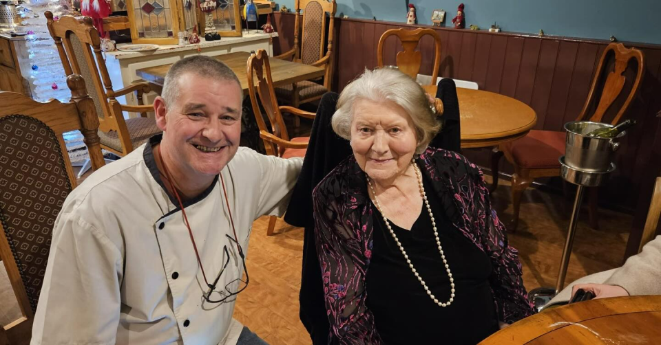 Chef Michael Newton-Young and actress Patricia Routledge posing together in a restaurant.
