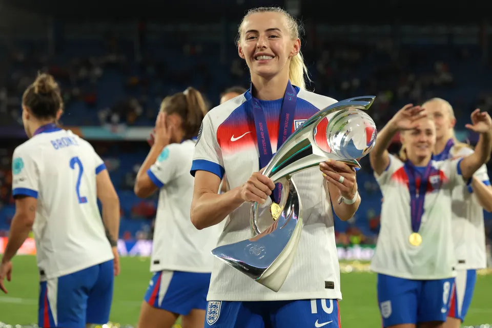 Chloe Kelly of England smiles as she holds up the UEFA Women's EURO trophy.