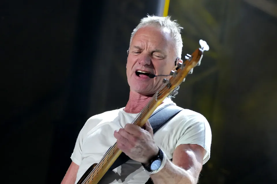 Sting performing onstage while playing bass guitar.