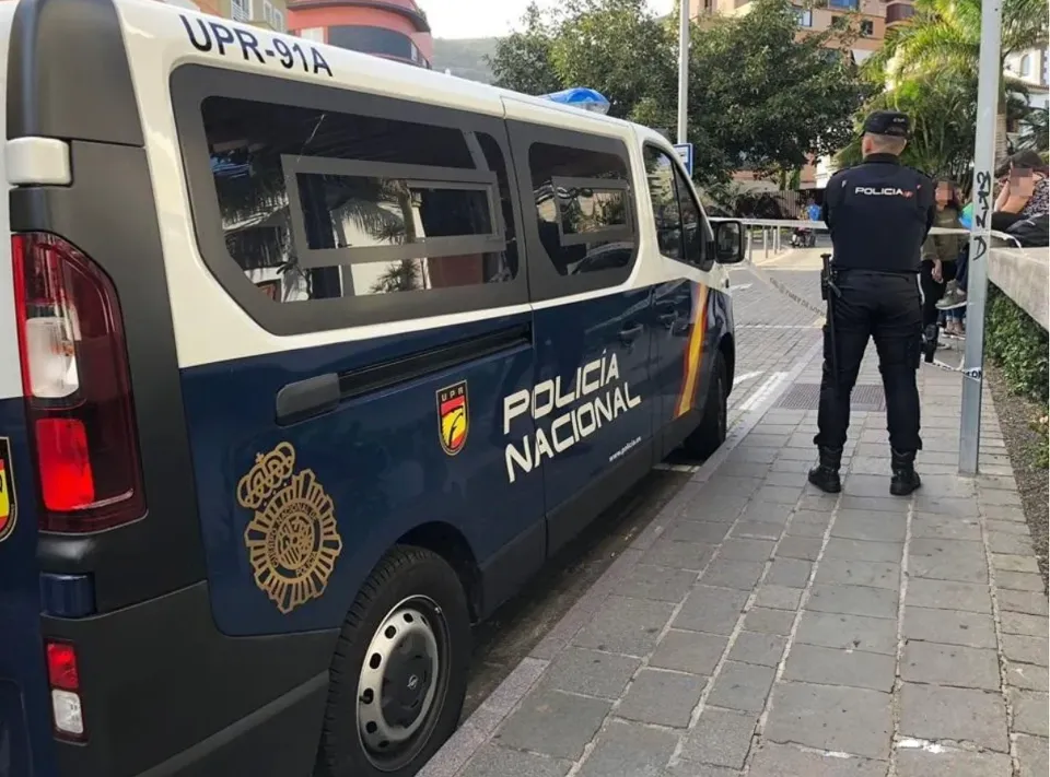 A Spanish National Police officer standing next to a police van.