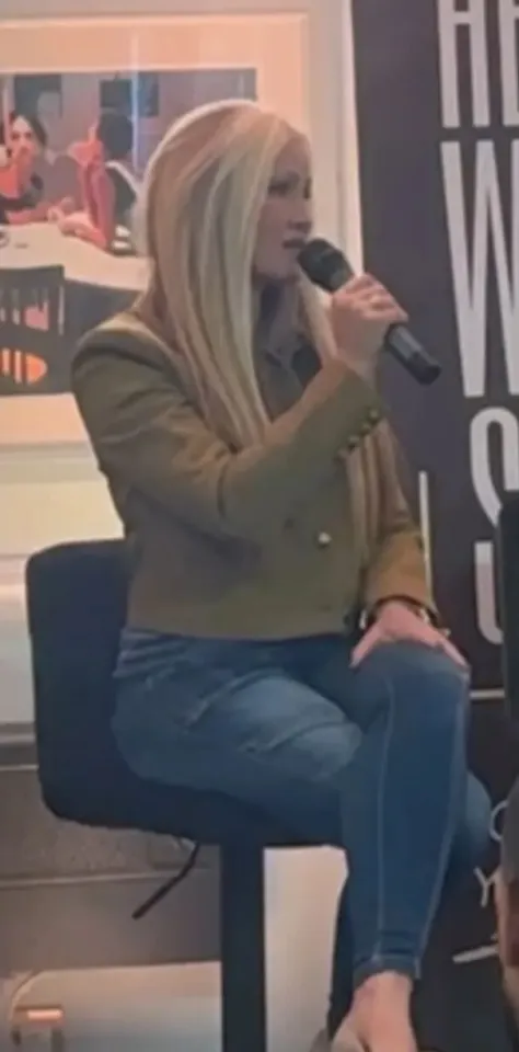 Caprice Bourret speaking into a microphone while seated.