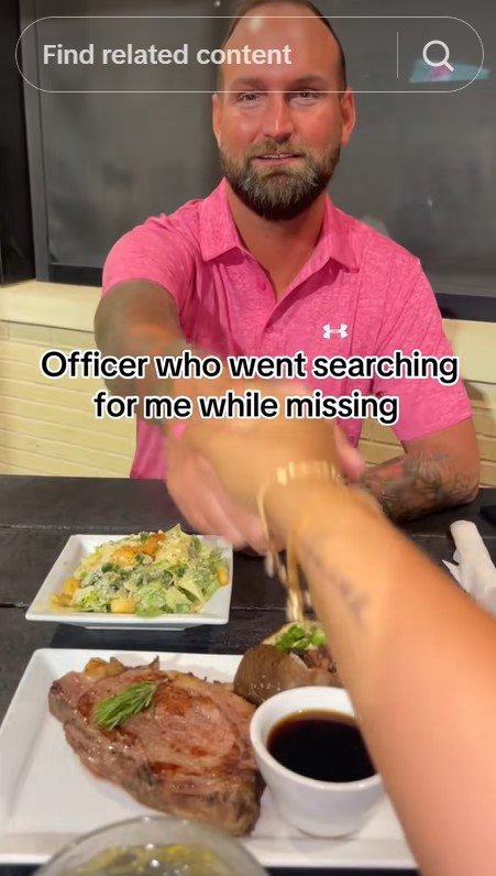 A man in a pink polo shirt across a table from a woman, shaking hands, with food on the table.