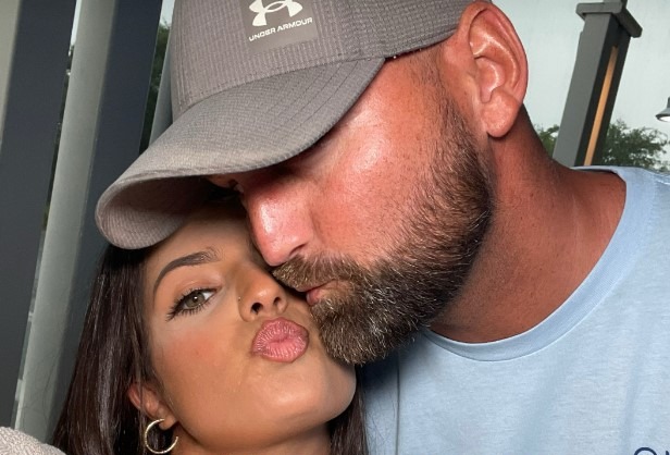A man with a beard kisses a woman on the cheek, with text overlay "Pick a picture of you and your partner & see what song TikTok gives you."