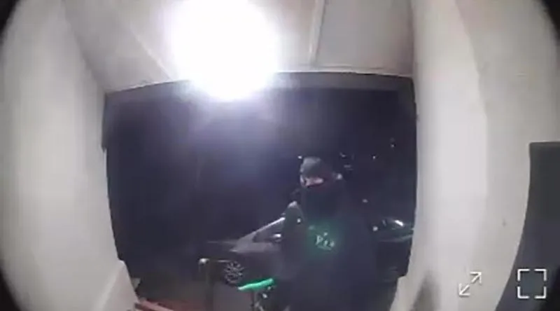 Video footage of an individual in dark clothing and a black face covering, possibly at the scene of the Peachaven Mosque arson.