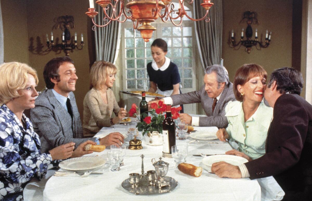 Party guests assemble around a dining table.