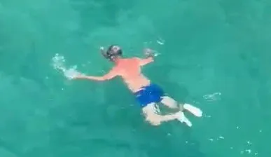 Peter Colville wearing blue shorts and a snorkel, swimming in the sea.