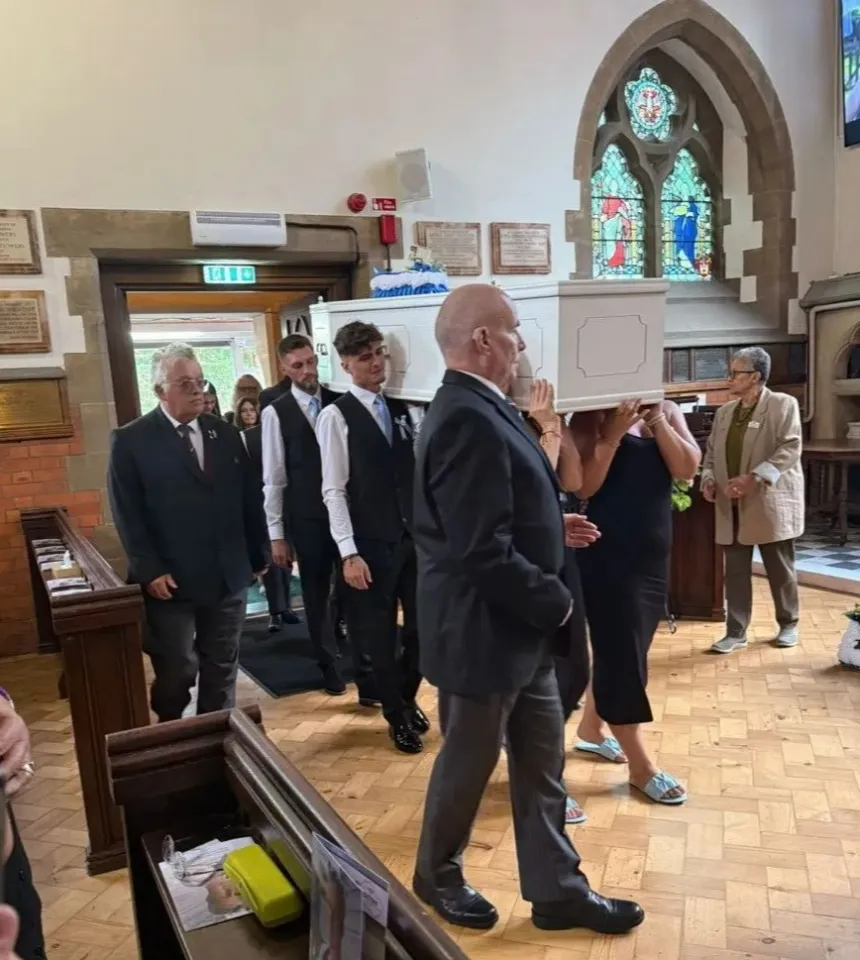 People carrying a white coffin into a church for Peter Colville's funeral.