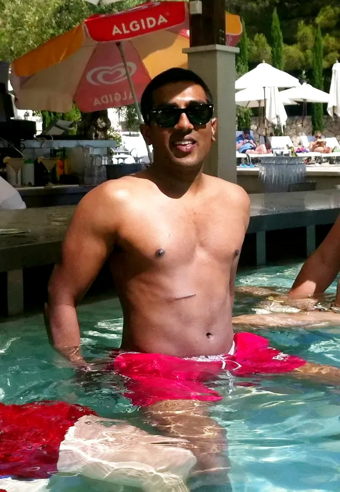 Nishanthan Gnanathas, known as Nish, standing in water up to his waist, wearing sunglasses and red swimming trunks.