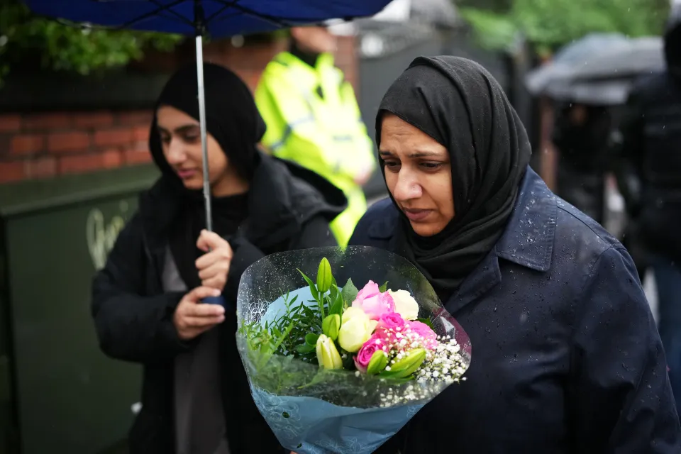 Two people leaving flowers in tribute after an attack on a synagogue in Manchester, England.