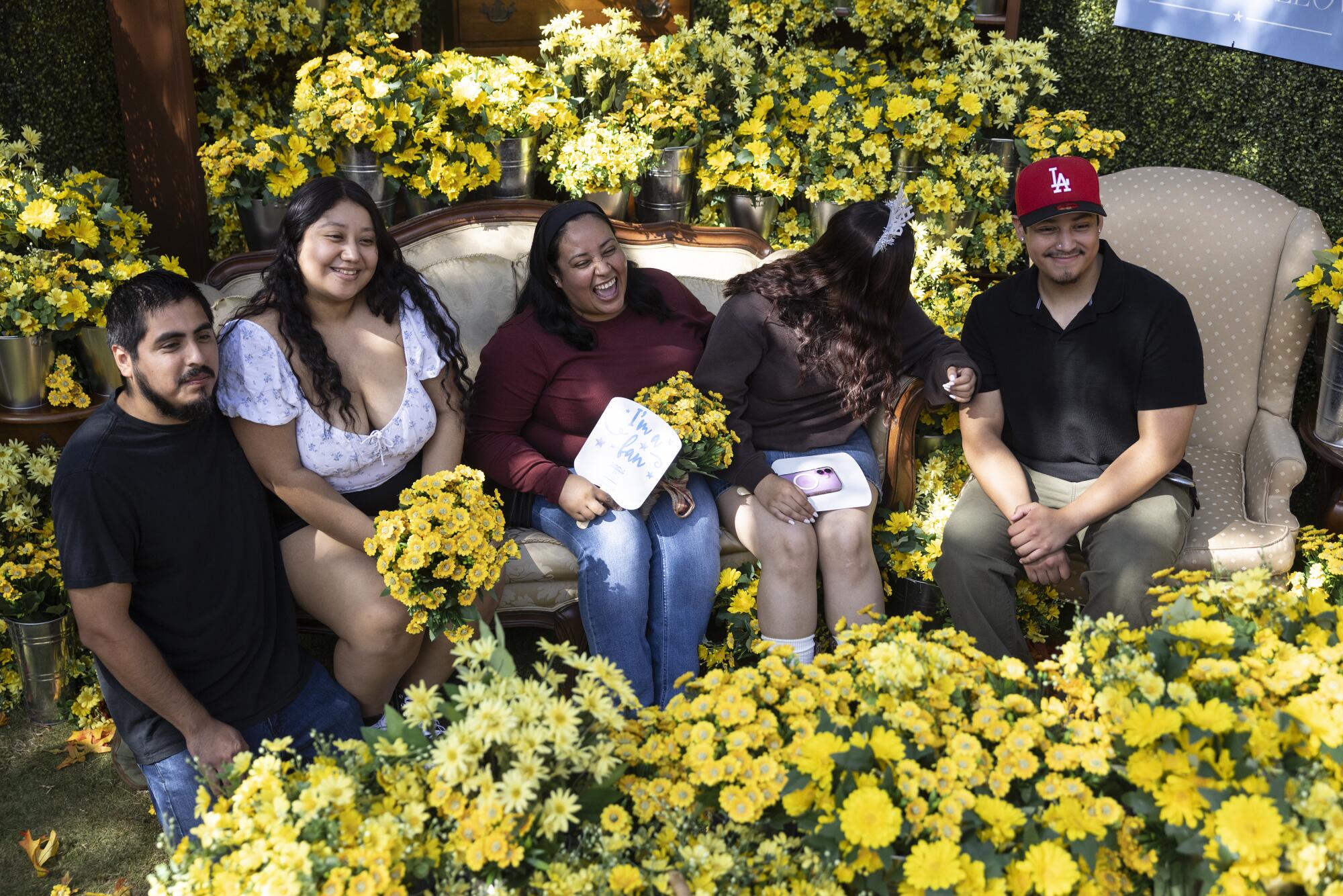 A photo of a group posing for a photo near a display of dozens of yellow daisies.