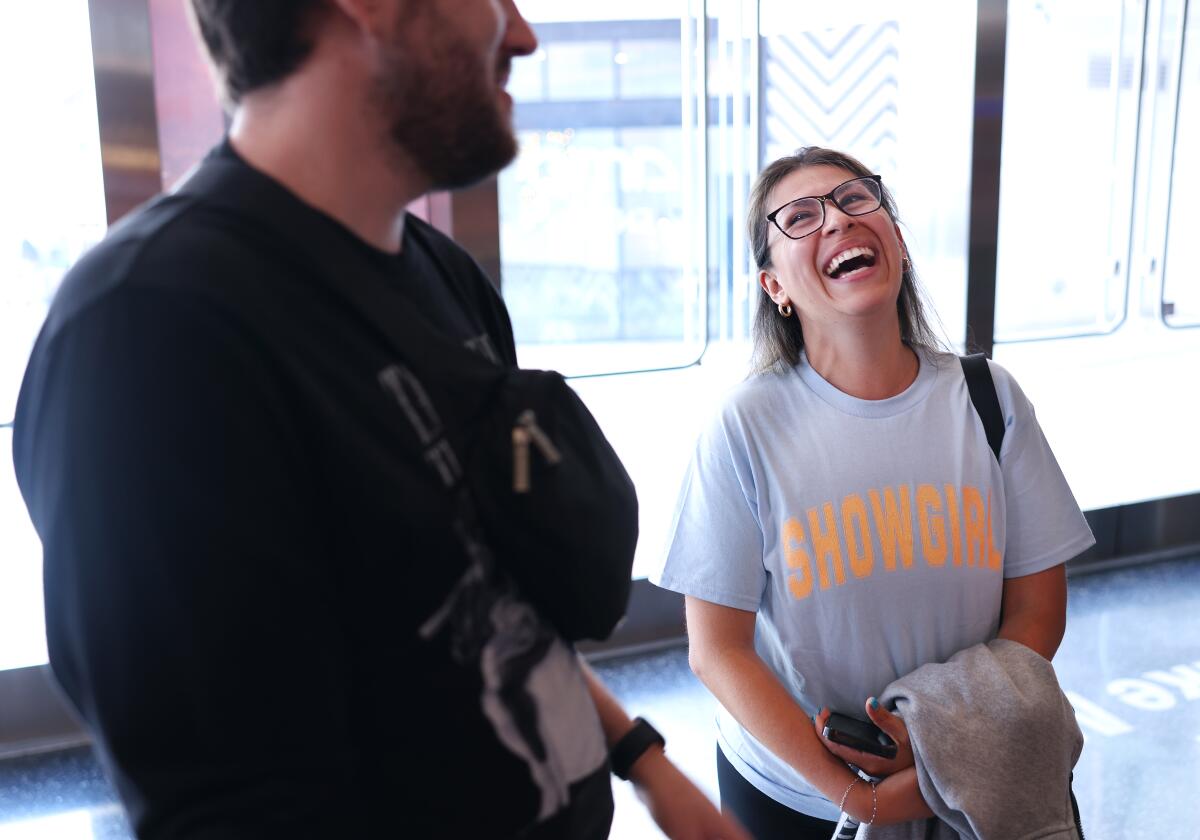Taylor Swift fans laugh in a movie theater.