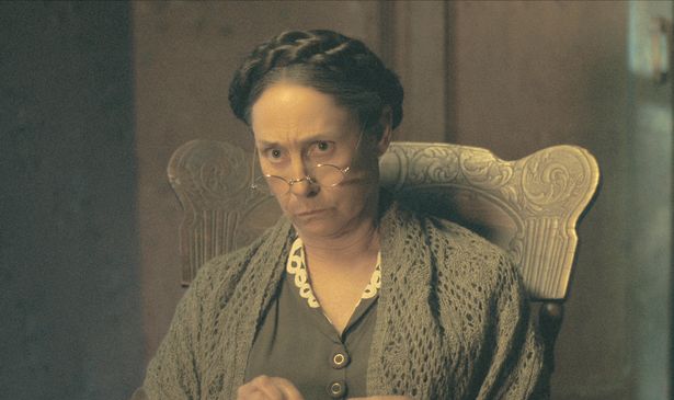 A woman in a chair looks serious 