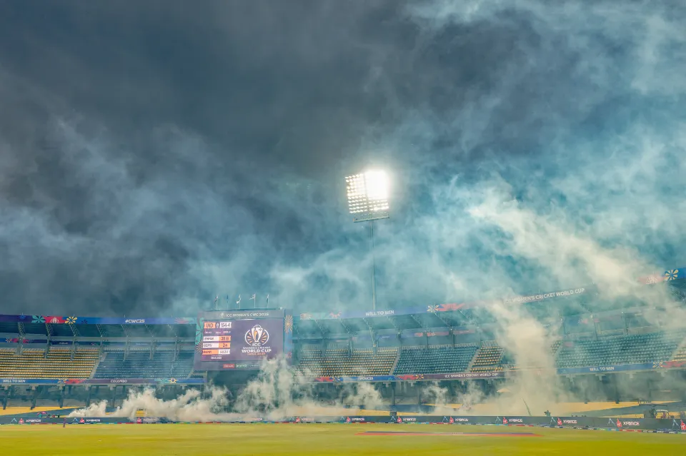 Smoke covers a cricket field and stadium during the ICC Women's Cricket World Cup match.