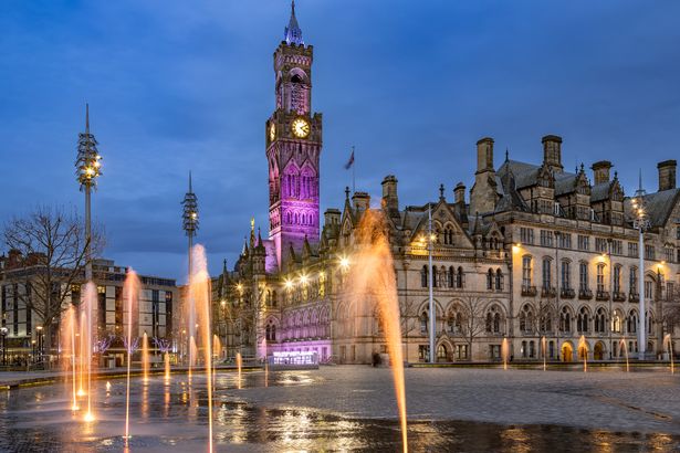 Dramatic night shot of Bradford City Hall reflected in the mirror pool in the city park.