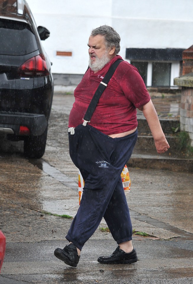 Brian Wilkinson walking in the rain with a shopping bag in the North of England.
