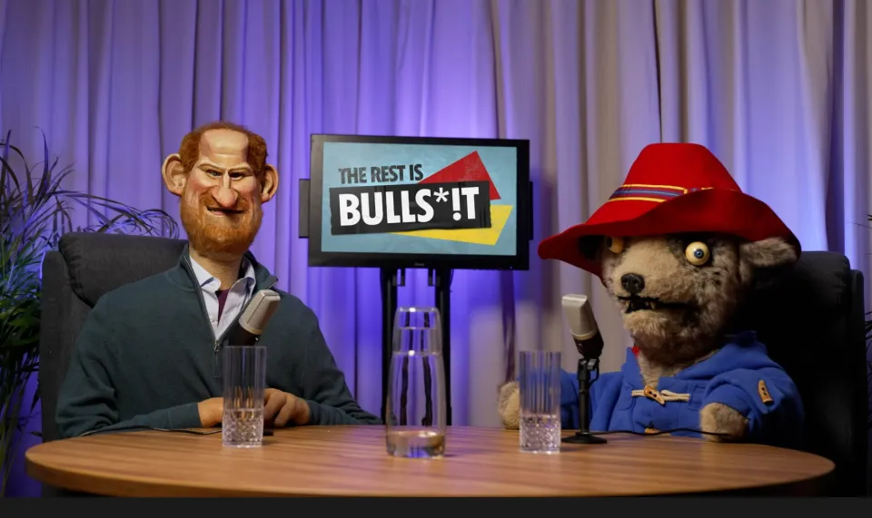 Illustration of Paddington Bear and Prince Harry puppets in a podcast scene with a screen displaying "THE REST IS BULLS*!T".