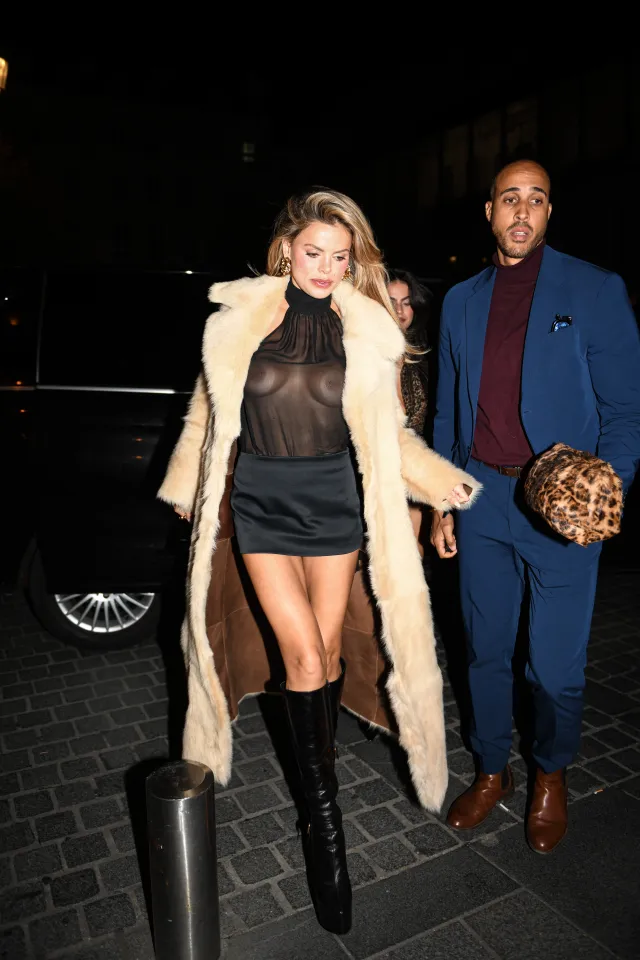 Brooks Nader arriving at Le Sienna Restaurant in Paris, France, wearing a fur coat, sheer top, and mini skirt, next to a man in a navy suit.