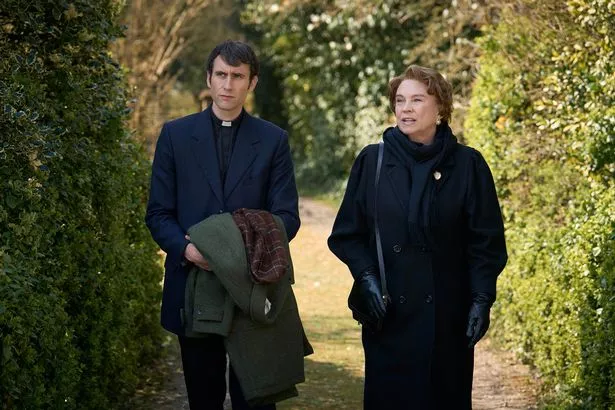 A man and a woman taking a walk as he holds a coat 