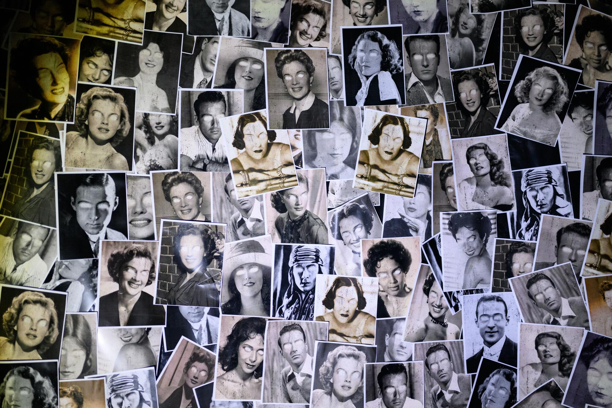 A wall filled with portraits with the eyes cut out.
